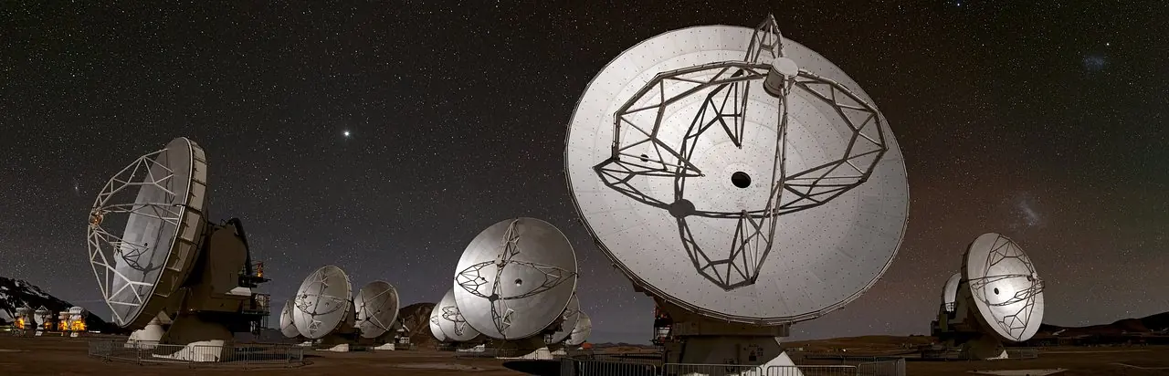 Un site d'observation la nuit, ses antennes tournees vers un ciel etoile.
