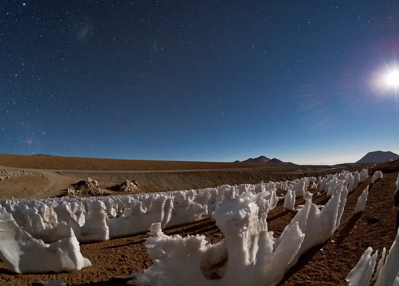 Des penitents de glace dresses sur un haut plateau, eclaires par la Lune, sous un ciel etoile.