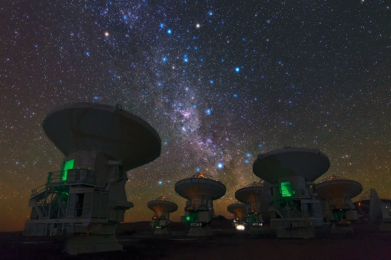 La Voie lactee australe au-dessus des antennes d'un radiotelescope, sur un haut plateau desertique.